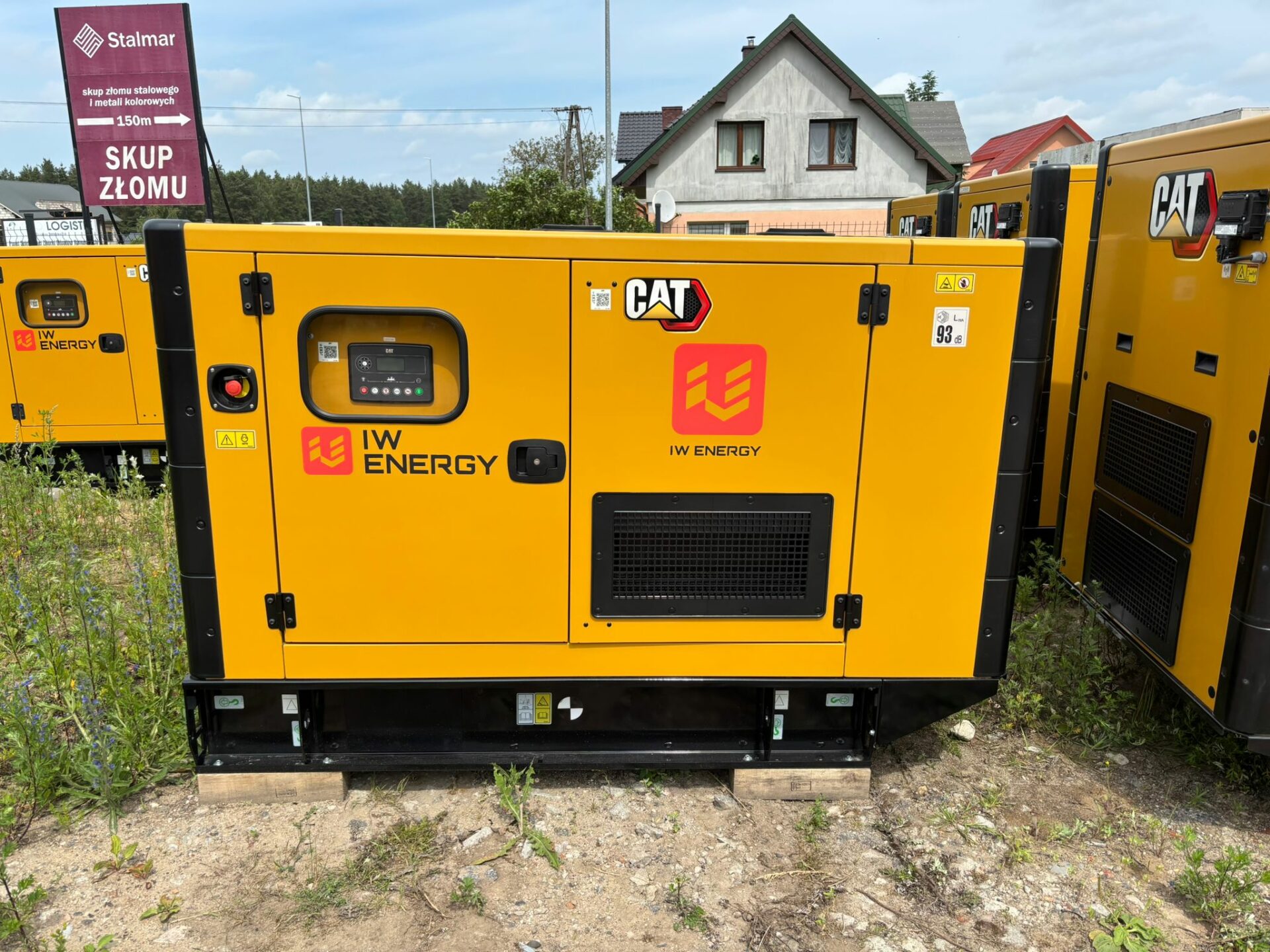 Agregat prądotwórczy marki CAT oznakowany logotypem IW Energy, przygotowany do wynajmu – urządzenie stojące na utwardzonym gruncie, gotowe do pracy w terenie.